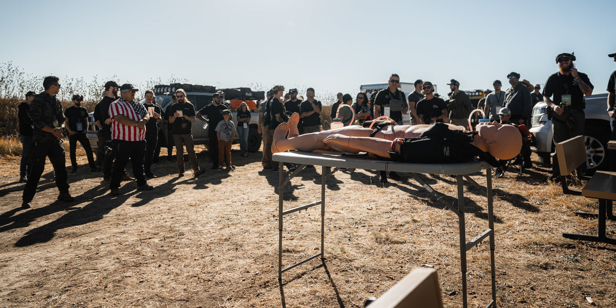 Direct Action Response Training class gathered around a trauma manikin at the range