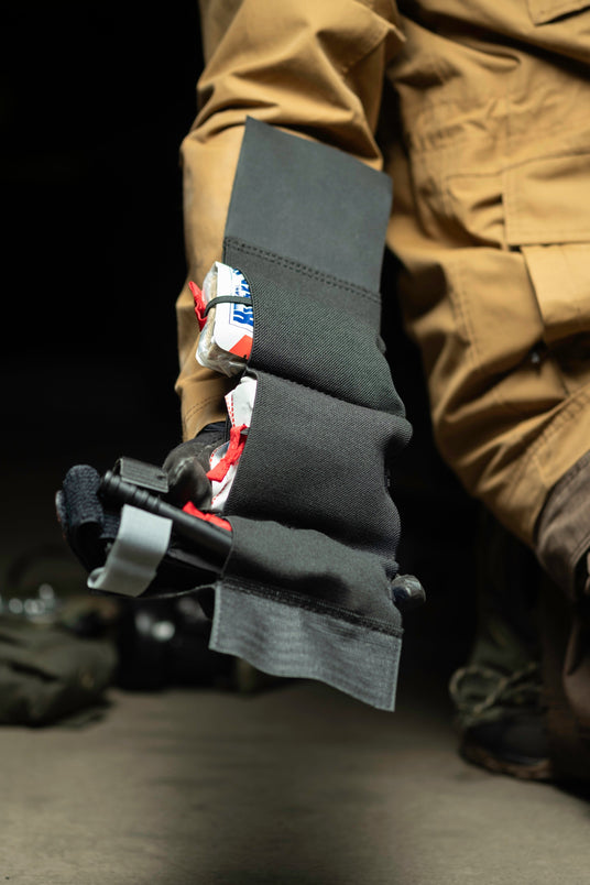 Elastic ankle rig loaded with tourniquet and trauma supplies held in hand