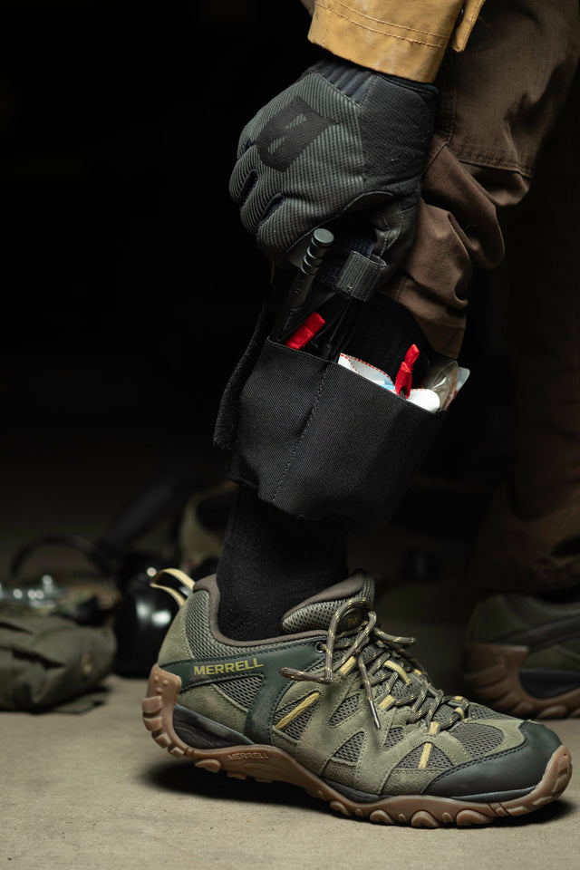Ankle trauma kit worn above a hiking shoe with tourniquet and supplies visible