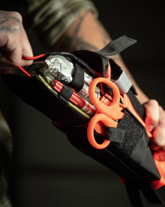 Opening the D.A.R.K. Trauma Kit pouch to pull the medical insert