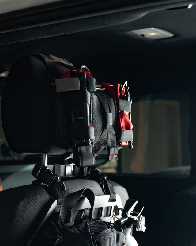 Black HEDR trauma kit mounted behind the headrest inside a vehicle