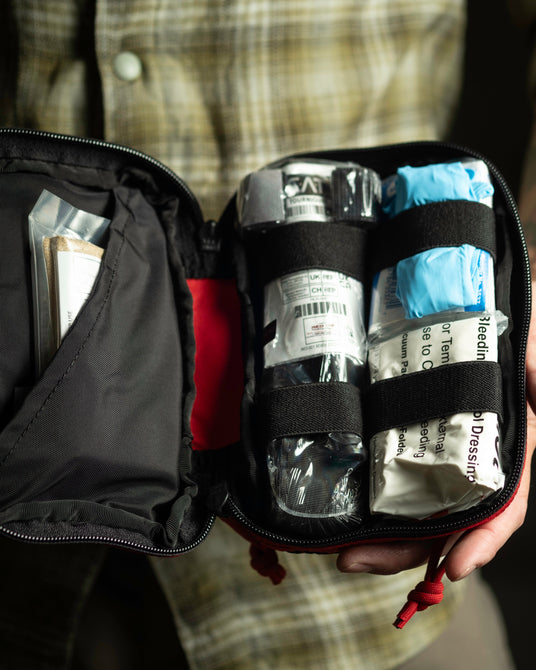 Trauma layer of the Ouch Pouch Plus with CAT tourniquet, gloves, and hemostatic dressing under elastic loops