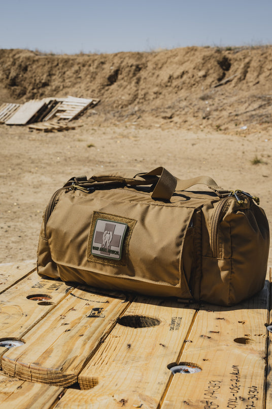 Coyote brown ST MIKE Bag trauma kit staged on a wooden spool at the range