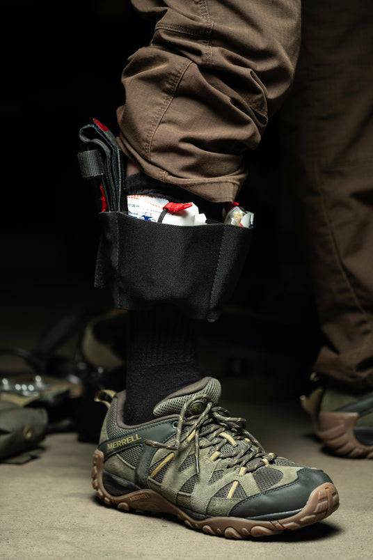 Reaching down to pull supplies from the ankle trauma kit by its red pull tabs