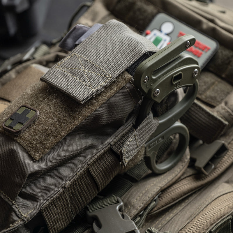 OD green D.A.R.K. Trauma Kit with RipShears stowed on top, mounted on a plate carrier
