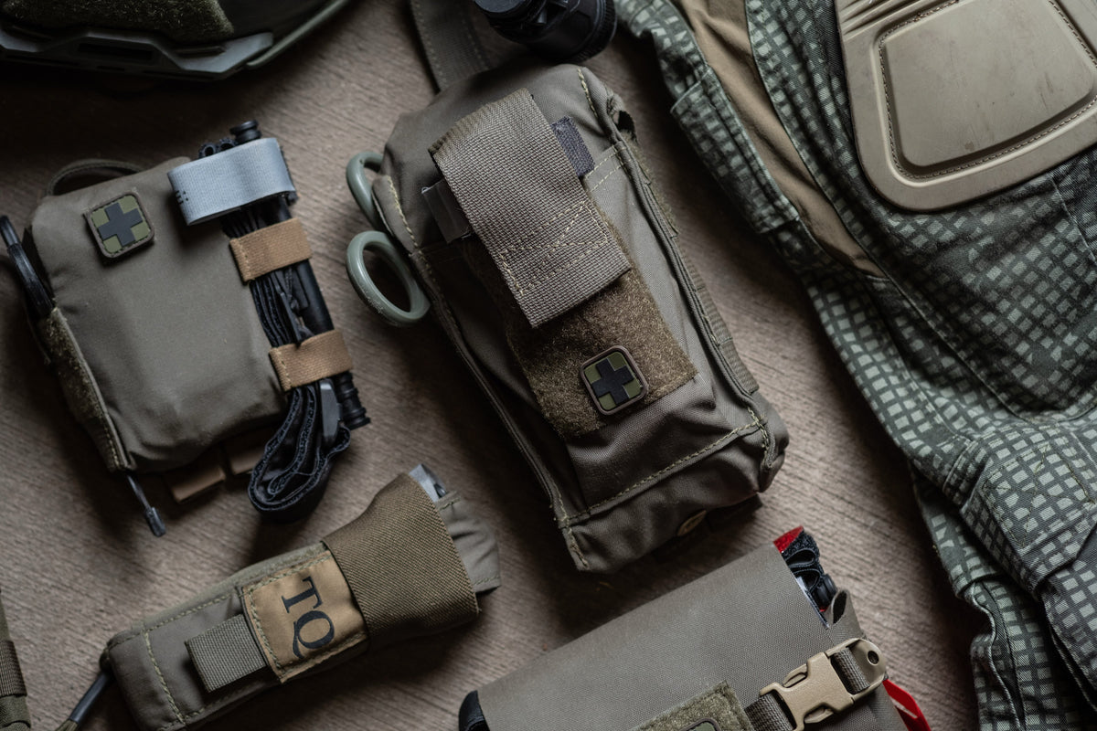 Compact everyday carry trauma kits and tourniquet pouch laid out on carry gear