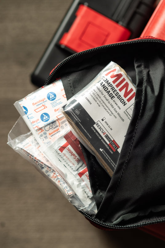 First aid flap pocket of the Ouch Pouch Plus holding bandages and a mini compression bandage