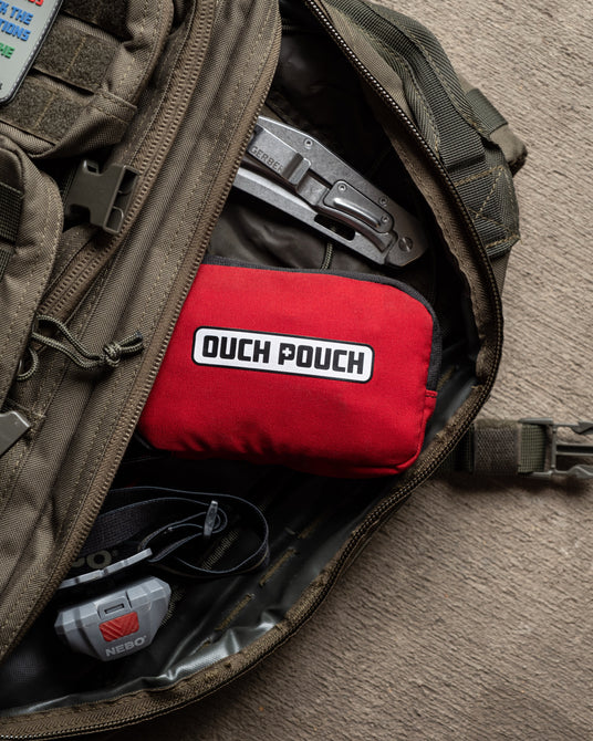 Ouch Pouch compact first aid kit tucked into a backpack pocket