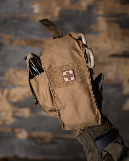 D.A.R.K. Slim Trauma Kit in hand showing the side tourniquet pouch and shears