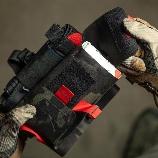 Gloved hands deploying the S.P.E.A.R. trauma kit by its red pull handle