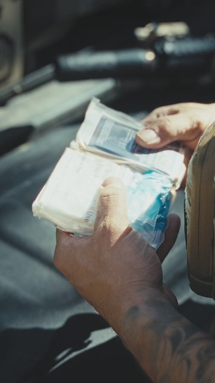 Pulling the Blue Line trauma kit from a cargo pocket